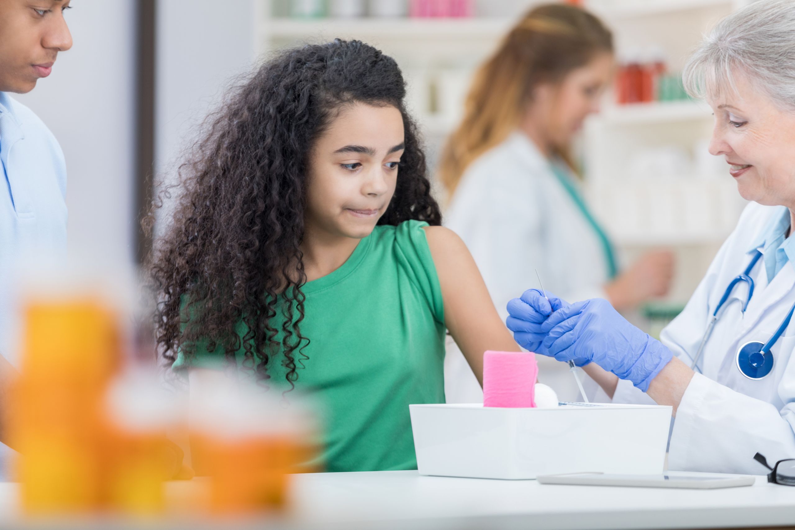 Brave preteen girl waits as pharmacist prepares her flu shot